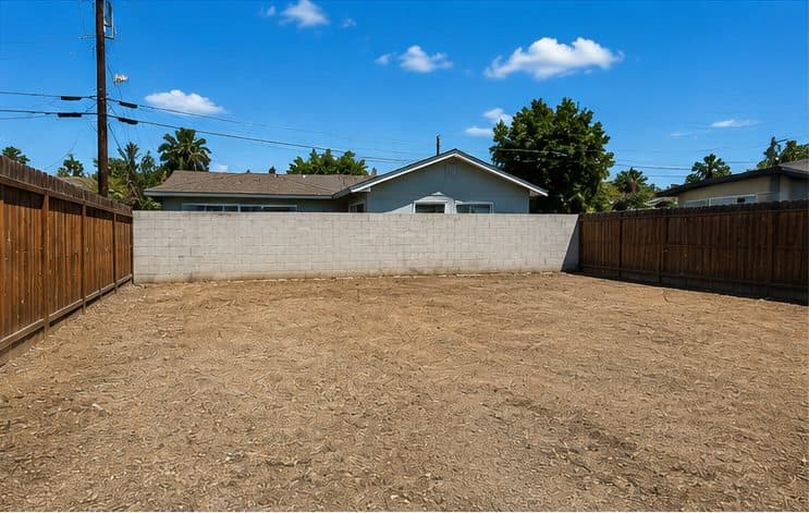 Bare dirt backyard behind a block wall before construction
